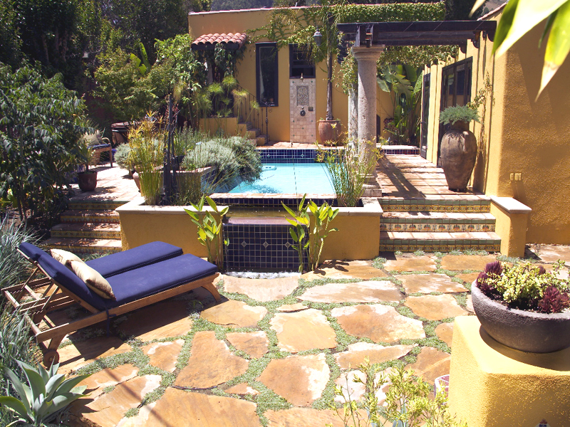 hot tub with paving stones, columns and lush plantings